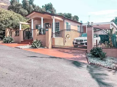 a house with a gate and a car parked in the driveway at Cozy beach home walking distance from ocean in Ventura