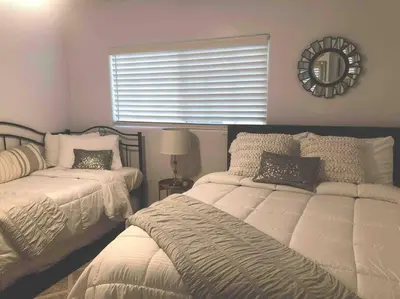 a bedroom with two beds and a mirror on the wall at Cozy beach home walking distance from ocean in Ventura
