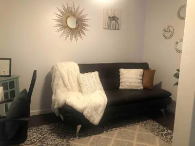 a living room with a black couch and a mirror at Cozy beach home walking distance from ocean in Ventura