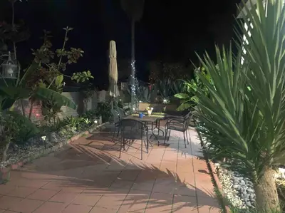 a table and chairs in a garden at night at Cozy beach home walking distance from ocean in Ventura