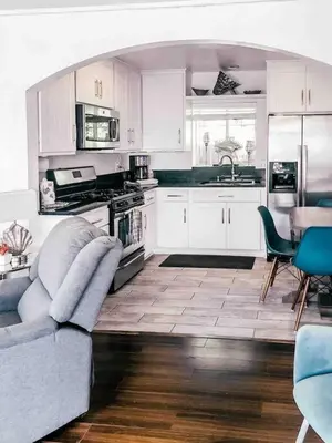 a kitchen with white cabinets and a blue couch in it at Cozy beach home walking distance from ocean in Ventura