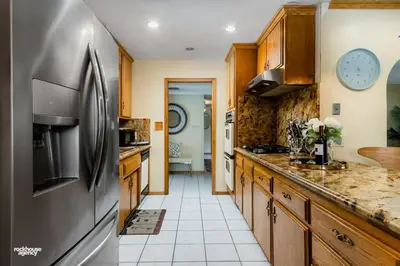 a kitchen with wooden cabinets and a stainless steel refrigerator at Cozy Hygge Home Centrally Located 2 King Beds in Bakersfield
