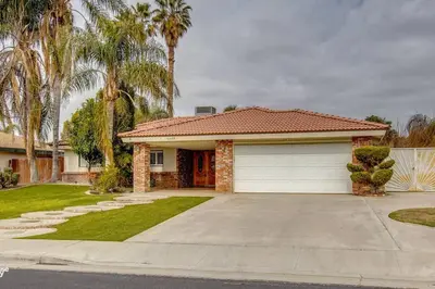 a house with a garage and palm trees at Cozy Hygge Home Centrally Located 2 King Beds in Bakersfield