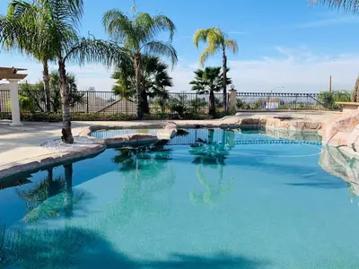 a swimming pool with palm trees and a fence at HighEnd Rooms in Mansion in Riverside