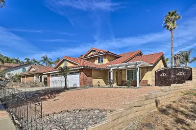 a house with a fence and a palm tree at Bright California Home with Patio Less Than 1 Mi to Hiking! in Corona