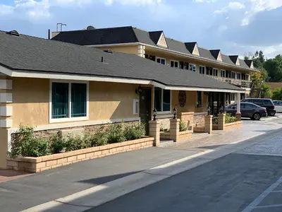 a building with cars parked in a parking lot at Walnut Inn & Suites West Covina in West Covina