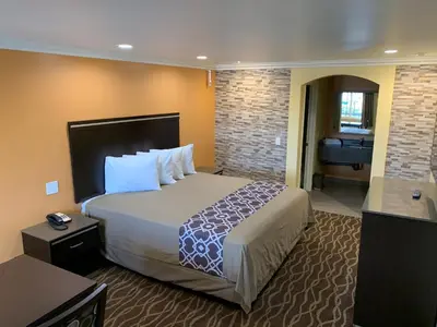 a hotel room with a large bed and a bathroom at Walnut Inn & Suites West Covina in West Covina