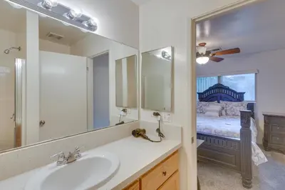 a bathroom with a sink and a mirror and a bed at Convenient Bakersfield Townhome with Patio! in Bakersfield