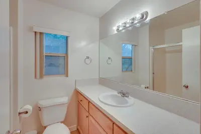 a bathroom with a toilet and a sink and a mirror at Convenient Bakersfield Townhome with Patio! in Bakersfield