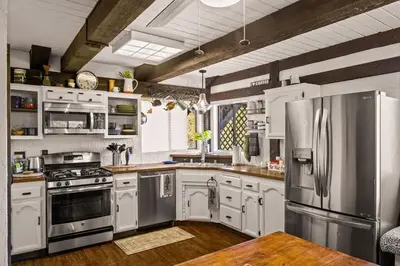 a kitchen with white cabinets and stainless steel appliances at The Lake Chalet in Crestline