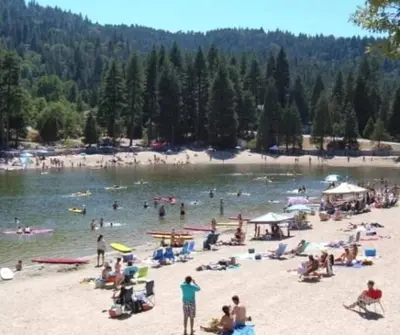 a group of people on the beach at a lake at The Lake Chalet in Crestline