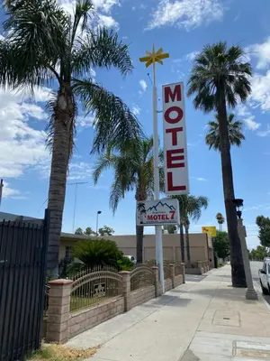 a sign for a motel on a sidewalk with palm trees at Downtown Motel 7 in San Bernardino