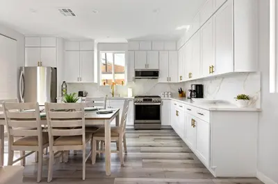 a kitchen with white cabinets and a table and chairs at Adorable 3 bedroom with Jacuzzi & more in Los Angeles