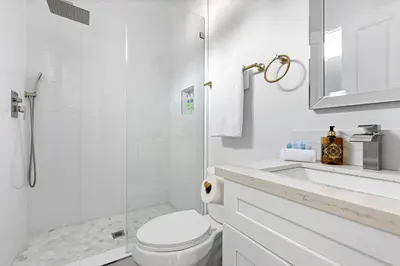 a white bathroom with a toilet and a shower at Adorable 3 bedroom with Jacuzzi & more in Los Angeles