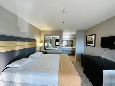 a bedroom with a large bed and a flat screen tv at Casa Blanca Hotel - Cypress, Buena Park in Cypress