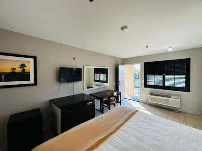 a bedroom with a bed and a desk and a table at Casa Blanca Hotel - Cypress, Buena Park in Cypress