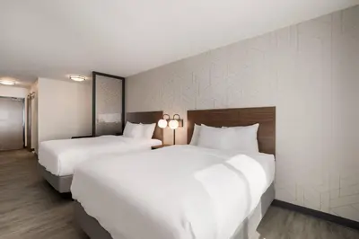 two beds in a hotel room with white sheets at Everhome Suites Corona in Corona