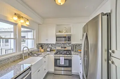 a kitchen with white cabinets and a stainless steel refrigerator at Carpinteria Apt with Hot Tub - 10 Min Walk to Beach! in Carpinteria