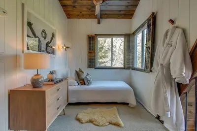 a bedroom with a bed and a dresser and window at Roots Mountain House Modern A-Frame in Lake Arrowhead