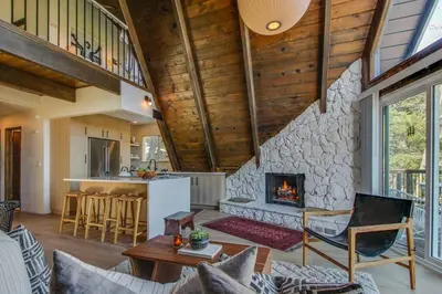 a living room with a stone fireplace in a house at Roots Mountain House Modern A-Frame in Lake Arrowhead
