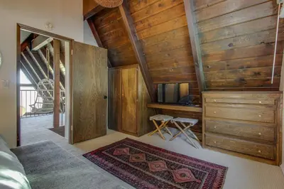 a bedroom with wooden walls and a tv and a rug at Roots Mountain House Modern A-Frame in Lake Arrowhead