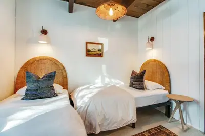 two beds in a room with white walls at Roots Mountain House Modern A-Frame in Lake Arrowhead