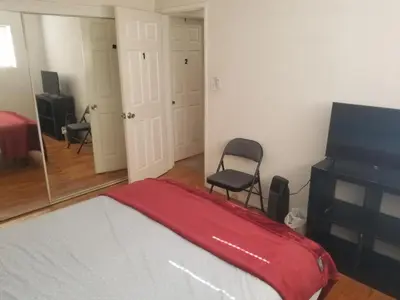 a bedroom with a bed and a chair and a television at Nearby Beach House in El Segundo