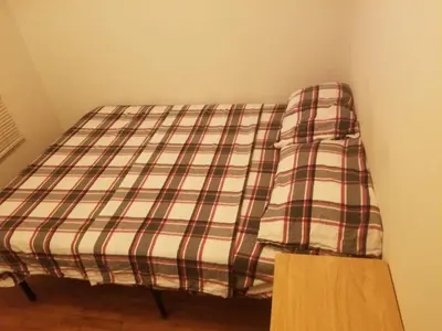 a bed in a room with a plaid sheet at Nearby Beach House in El Segundo