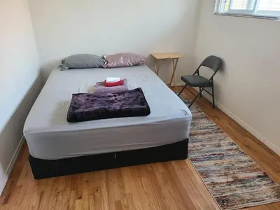 a bed in a small room with a chair at Nearby Beach House in El Segundo