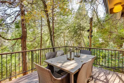 a wooden table and chairs on a deck with trees at Spacious Retreat 13 Mi to Snow Valley Mtn Resort! in Lake Arrowhead