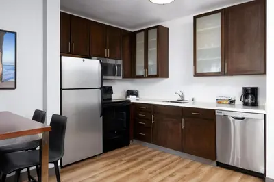 a kitchen with a white refrigerator and wooden cabinets at Residence Inn by Marriott Los Angeles Redondo Beach in Redondo Beach