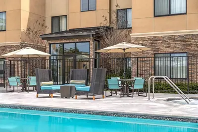 a pool with chairs and umbrellas next to a building at Residence Inn by Marriott Los Angeles Redondo Beach in Redondo Beach