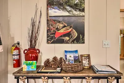 a table with books and a vase on it at Steps to Lake Cabin with Deck in Lake Arrowhead in Lake Arrowhead