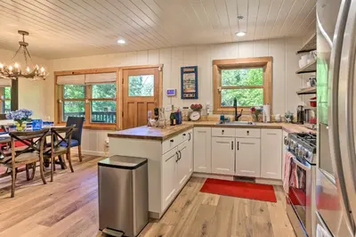 a kitchen with white cabinets and a dining room at Steps to Lake Cabin with Deck in Lake Arrowhead in Lake Arrowhead