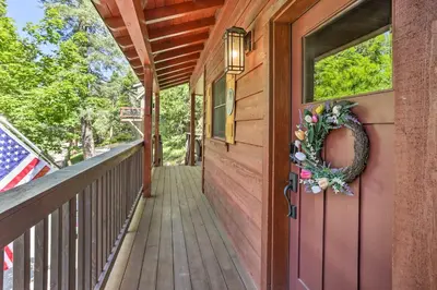 a porch with a wreath on the door and an american flag at Steps to Lake Cabin with Deck in Lake Arrowhead in Lake Arrowhead