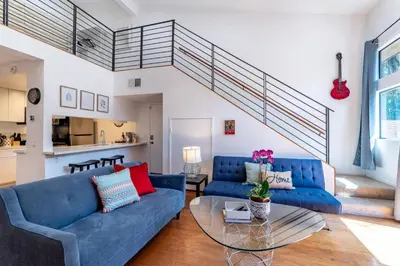 a living room with blue couches and a glass table at Franklin Hollywood Bowl Loft in Los Angeles