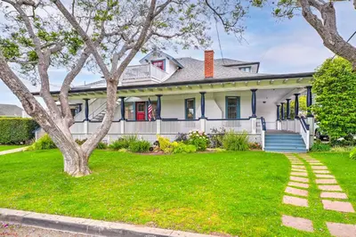 a white house with a tree in the yard at Cozy Carpinteria Apartment Walkable Location in Carpinteria