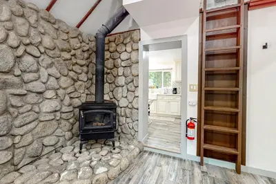 a room with a stone wall with a fireplace at Top Town Retreat in Crestline