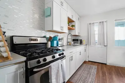 a kitchen with a stove and white cabinets at The Green Haven, 1 Minute Walk to the Beach and Restaurants, King Beds, Beach Amenities in Ventura