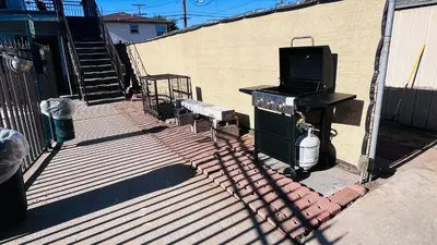 a patio with a table and a television and a bench at Lanai Motel in Alhambra