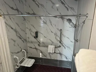 a bathroom with a shower with a glass door at Lanai Motel in Alhambra