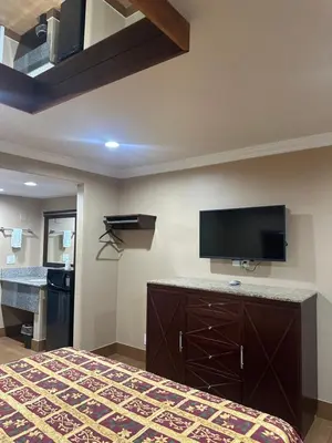 a hotel room with a bed and a flat screen tv at Stardust inn in Azusa