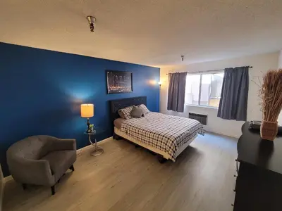 a bedroom with blue walls and a bed and a chair at Deluxe Hotel Style Unit in Los Angeles