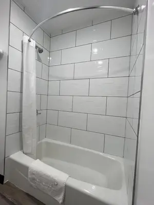 a white bathroom with a tub and a towel at Sunshine Motel in Long Beach
