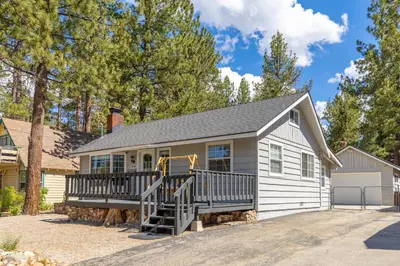a large white house with a large deck at Bayview Bungalow - Cabin with Hot Tub One Block from Big Bear Lake! in Big Bear Lake