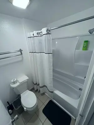 a white bathroom with a toilet and a shower at Bposhtels Anaheim in Anaheim