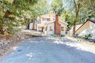 a house with a fence in front of a driveway at Treelands Lodge in Crestline