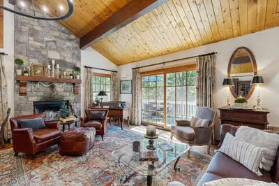a living room with a stone fireplace and furniture at Treetop Cottage in Running Springs
