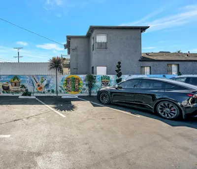 a black car parked in a parking lot in front of a building at Royal Hawaiian Inn - Mid City, Los Angeles in Los Angeles