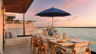 a table with chairs and an umbrella on a balcony at Matador by AvantStay Ocean Front Malibu Pad w Rooftop Patio in Topanga